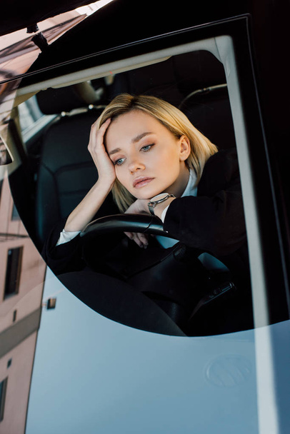 boos blonde jonge vrouw zittend in moderne auto  - Foto, afbeelding