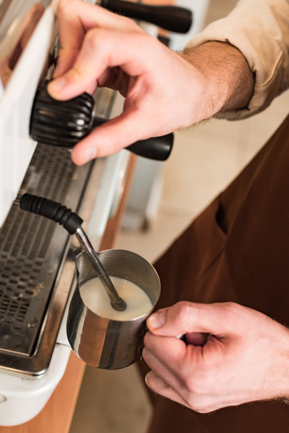Cropped view of barista filling up steel milk jug - Photo, Image