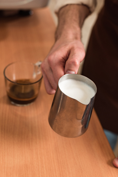 Cropped view of barista holding steel milk jug - Photo, Image