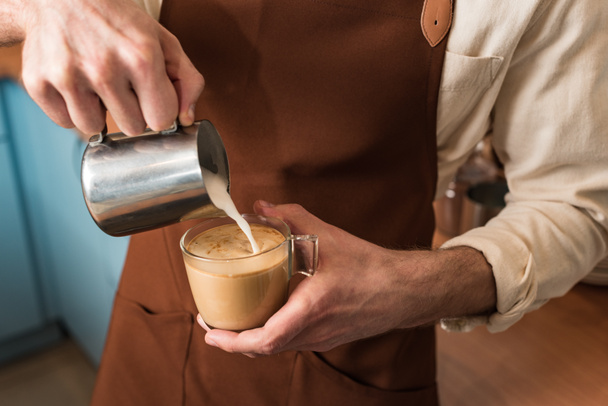 Cropped view of barista pouring milk in coffee - Zdjęcie, obraz