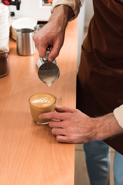 Viljelty näkymä barista kaatamalla maitoa kahviin
 - Valokuva, kuva