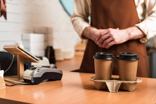 Kahverengi önlük ve tek kullanımlık kahve fincanbarista kırpılmış görünümü - Fotoğraf, Görsel