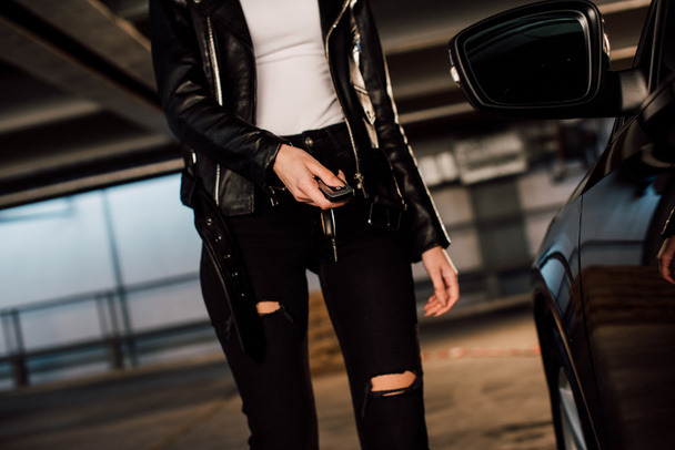cropped view of woman holding key in parking near black automobile  - Фото, зображення
