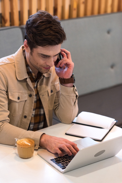 Freelancer sonriente en chaqueta hablando en smartphone en cafetería
 - Foto, imagen