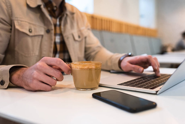 Vágott kilátás szabadúszóként csésze kávé gépelés laptop billentyűzet - Fotó, kép