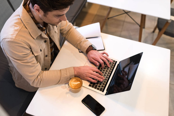 Hoge hoek weergave van Freelancer typen op laptop toetsenbord in café - Foto, afbeelding