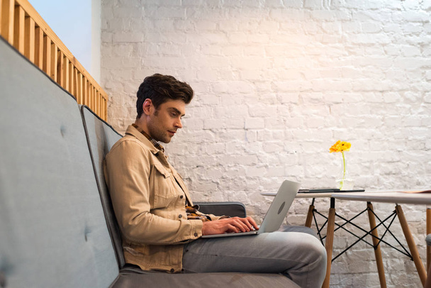 Freelancer in jacket and jeans working with laptop in cafe - Фото, зображення