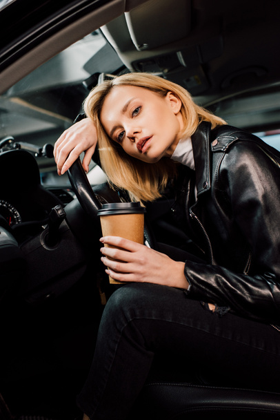 Tiefansicht des blonden Mädchens mit Pappbecher im Auto  - Foto, Bild