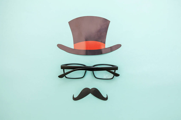 Happy Father's day concept. Sign of hat mustache with glasses isolated on pastel blue background. Man silhouette symbol - Photo, Image