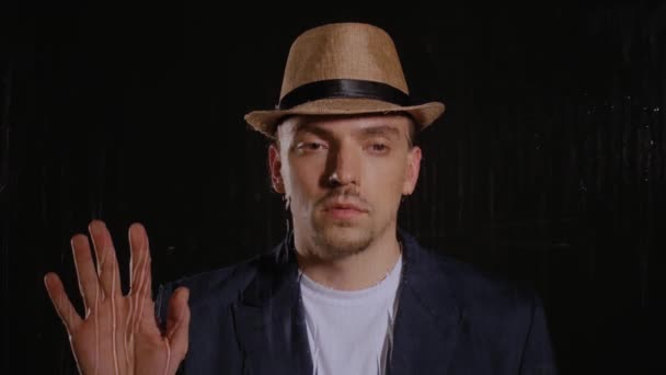 L’homme dans un chapeau et la veste touche le verre - Séquence, vidéo