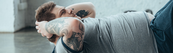 tiro panorámico de hombre tatuado con sobrepeso haciendo ejercicio sentado en el centro deportivo
 - Foto, imagen