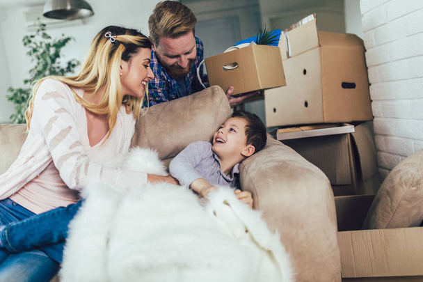Happy family with cardboard boxes in new house at moving day. - 写真・画像