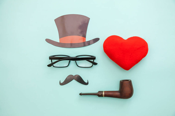 Happy Father's day concept. Sign of hat mustache with pipe glasses red heart isolated on pastel blue background. Man silhouette symbol - Photo, Image