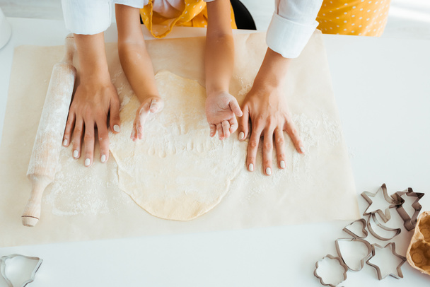 top view of mother and daughter with dough, rolling pin and dough molds on table - Foto, immagini