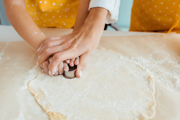 cropped view of mother and daughter using dough molds on dough - Foto, Bild