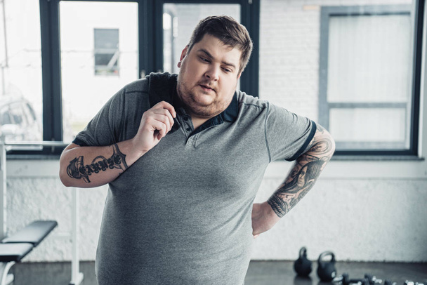 overweight tattooed man holding towel at sports center - Foto, imagen