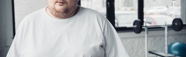plano panorámico del hombre tatuado con sobrepeso en camiseta blanca en el centro deportivo
 - Foto, imagen