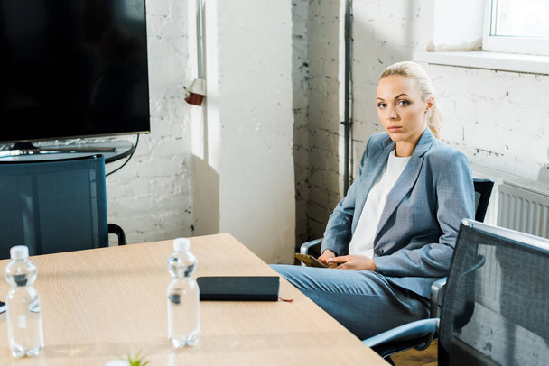 attraktive blonde Businesstrainerin sitzt im Konferenzraum und blickt in die Kamera  - Foto, Bild
