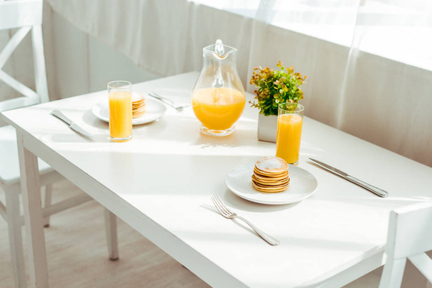 sweet pancakes with fresh orange juice served for breakfast on white table - Fotografie, Obrázek