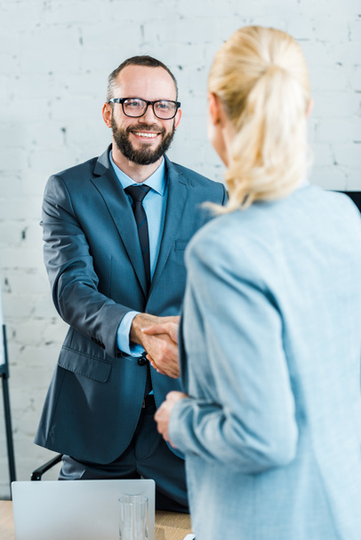 enfoque selectivo de entrenador de negocios feliz estrechando la mano con la mujer de negocios rubia
  - Foto, Imagen