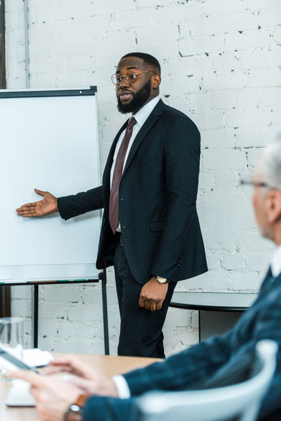 foco seletivo de belo treinador de negócios afro-americano falando e gesticulando perto do quadro branco
  - Foto, Imagem