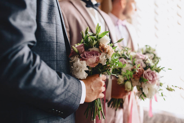Le marié tient un bouquet de mariage dans ses mains
 - Photo, image