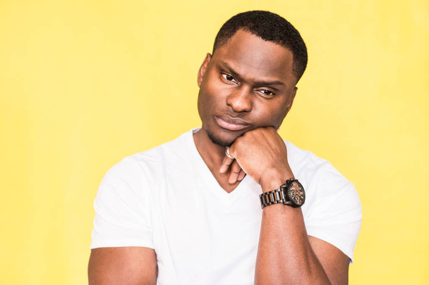 Pensive dark skinned man, has serious expression, poses against yellow background. - Foto, Imagen
