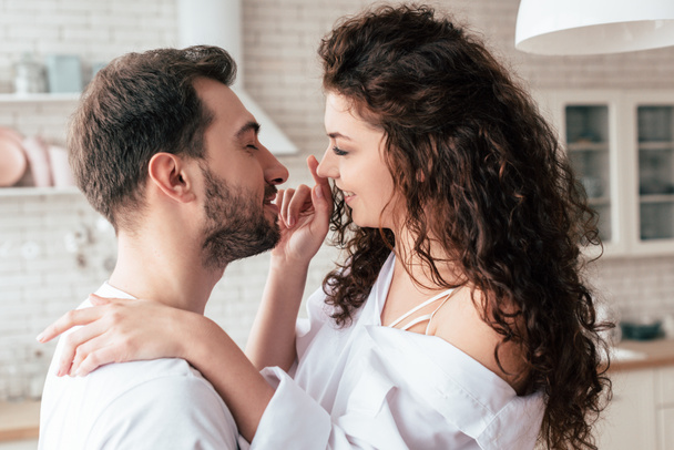 smiling loving couple in white clothes embracing in kitchen  - Foto, immagini
