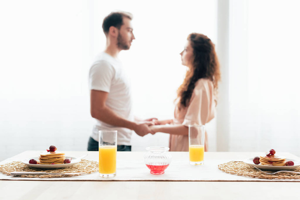 foyer sélectif de couple tenant la main avec des crêpes et du jus d'orange au premier plan
 - Photo, image