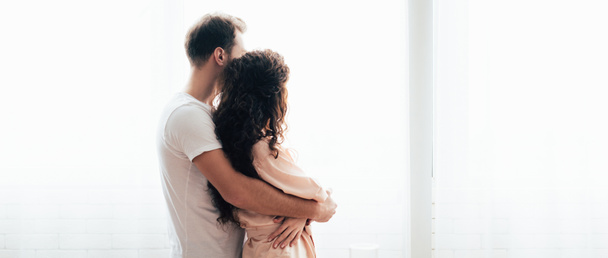 panoramic shot of man embracing girlfriend and looking away - Photo, Image