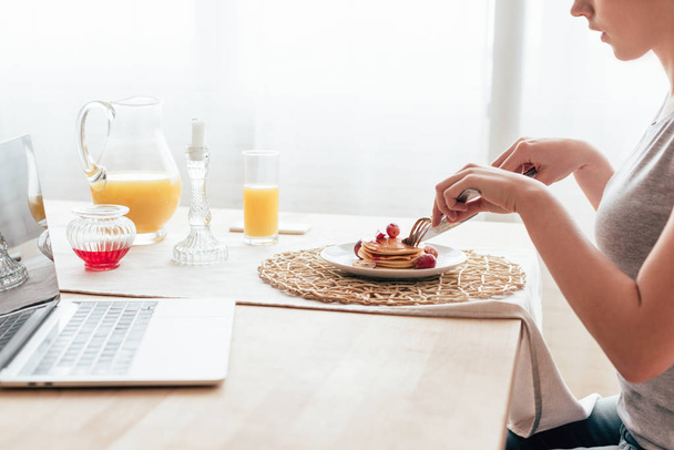 обрезанный вид молодой женщины, которая ест блинчики по утрам
 - Фото, изображение