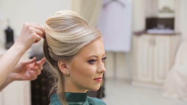 Close-up shot of a girl with long blond hair came to the stylist to make a fit. The hairdresser curls her client, makes a hairstyle for a client. People, beauty salons, makeup, coiffure - Footage, Video