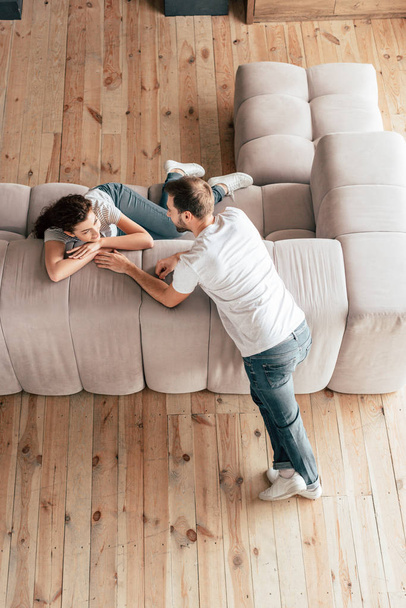overhead view of happy couple looking at each other in living room - Photo, Image