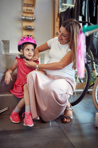 Beautiful pregnant mother to shopping new helmet for her girl in - Foto, imagen