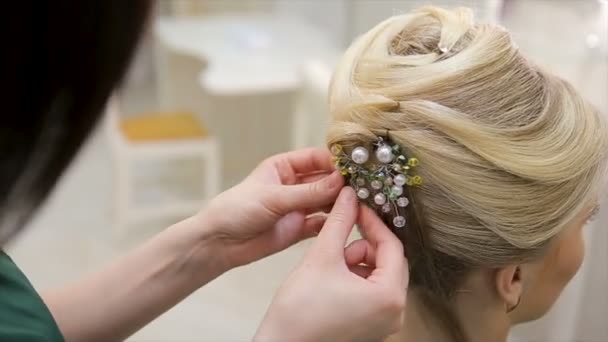 Fodrász tulajdonít a díszítés a haj egy fiatal szőke hajú nő, közelről - Felvétel, videó