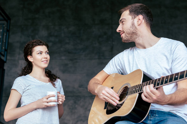 アコースティックギターを弾いてガールフレンドを見ている男の低角度の視点 - 写真・画像