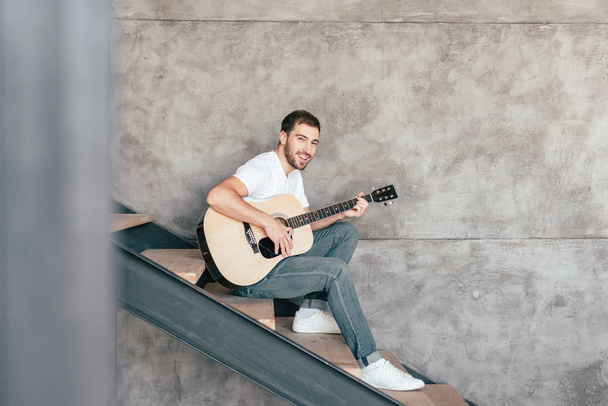 homme barbu souriant assis sur les escaliers et jouant de la guitare acoustique
 - Photo, image
