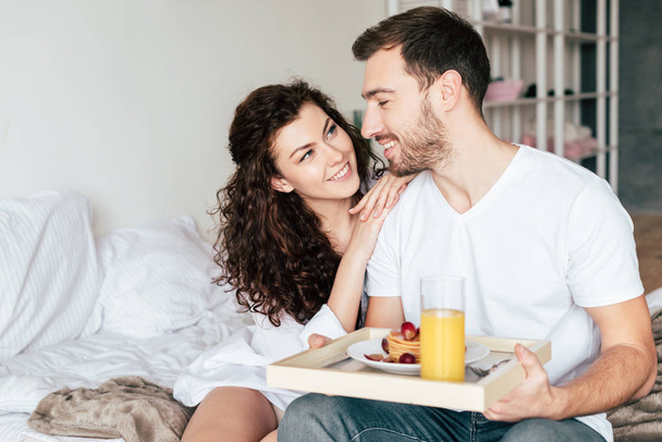 couple looking at each other while having breakfast in bed - Foto, imagen