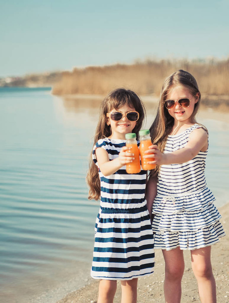 Οι μικροί φίλοι πίνουν χυμό στην παραλία. - Φωτογραφία, εικόνα
