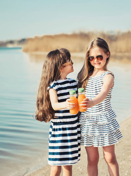 Little friends drink juice on the beach. - Photo, Image