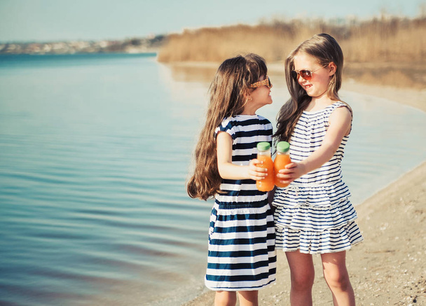 Little friends drink juice on the beach. - Photo, Image