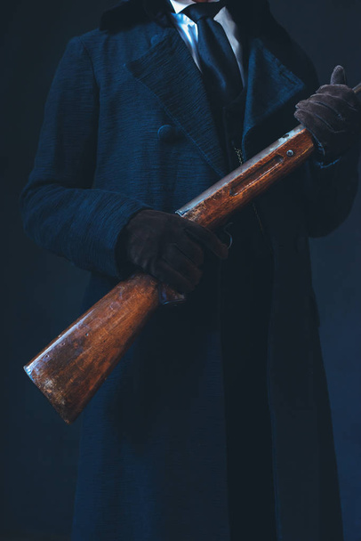 Homem de casaco preto comprido segurando rifle
. - Foto, Imagem