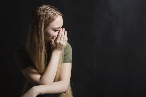 Trieste jonge vrouw gaat huilen in een zwarte achtergrond - Foto, afbeelding