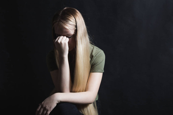 Sad young woman going to cry in a black background - Photo, Image