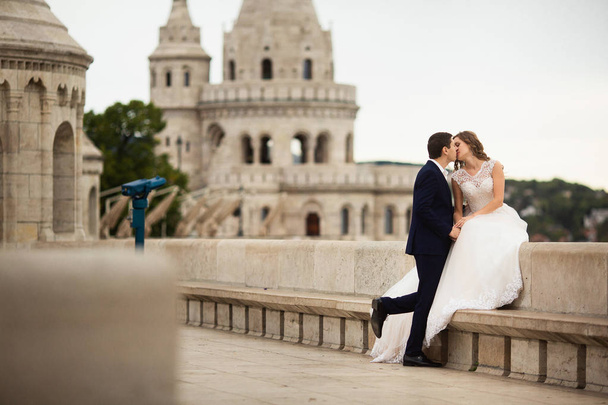 ブダペスト、ハンガリーの漁師の砦でキスをする新婚夫婦の若い美しいスタイリッシュなペア - 写真・画像