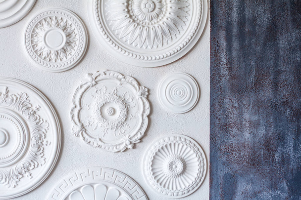 A two-color background, gray decorative plaster and a white wall with several white ceiling rosettes - Photo, Image