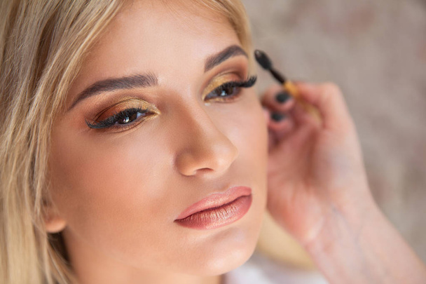 A make-up artist makes a make-up for a smaptic blonde girl - Φωτογραφία, εικόνα