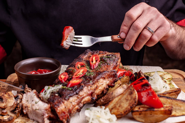 Delicious barbecued ribs seasoned with fresh herbs, cabbage salad, backed potato on an old rustic wooden chopping board - Photo, Image