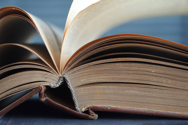Extreme close-up of an open book on a wooden surface against the background of a gray wall, the concept of education and training. - Photo, Image