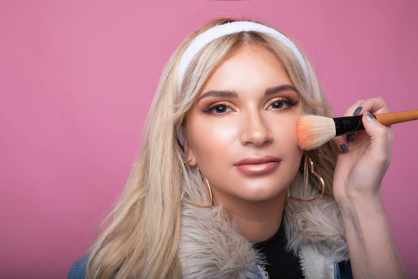 A make-up artist makes a make-up for a smaptic blonde girl - Fotó, kép